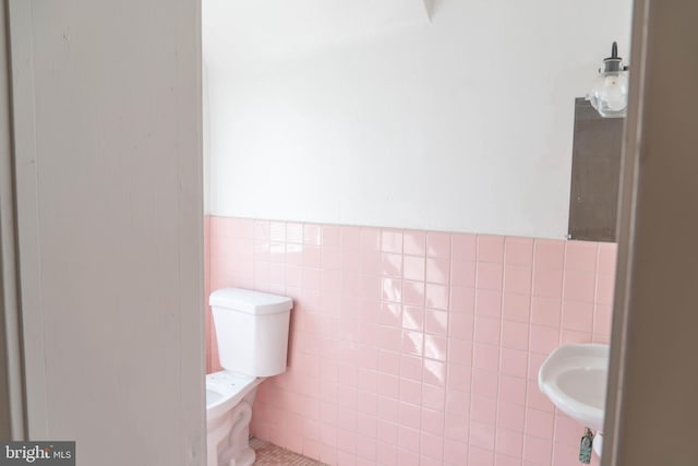 bathroom with toilet and tile walls