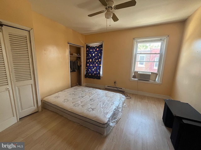 bedroom featuring light wood-type flooring, cooling unit, ceiling fan, and a baseboard heating unit