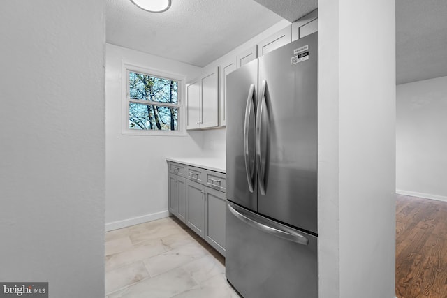 kitchen featuring gray cabinets, stainless steel fridge, light hardwood / wood-style flooring, and a textured ceiling