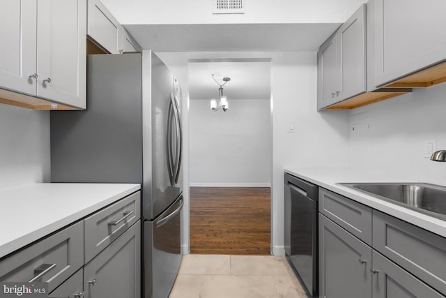 kitchen featuring sink, stainless steel appliances, gray cabinets, and light hardwood / wood-style flooring