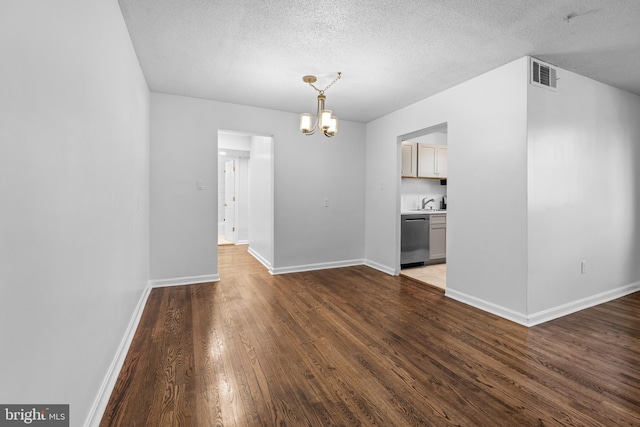 spare room with dark hardwood / wood-style flooring, a chandelier, a textured ceiling, and sink