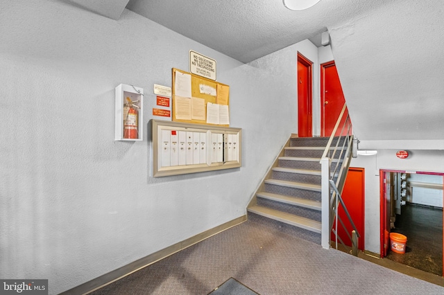 stairs featuring carpet, a textured ceiling, and mail boxes