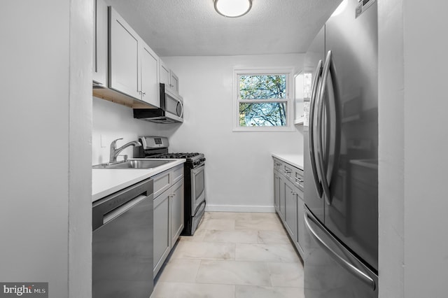 kitchen with gray cabinetry, sink, a textured ceiling, and appliances with stainless steel finishes