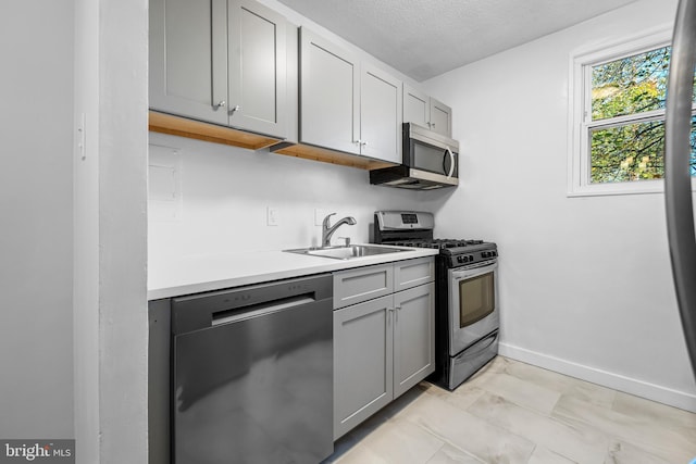 kitchen featuring gray cabinetry, sink, a textured ceiling, and appliances with stainless steel finishes