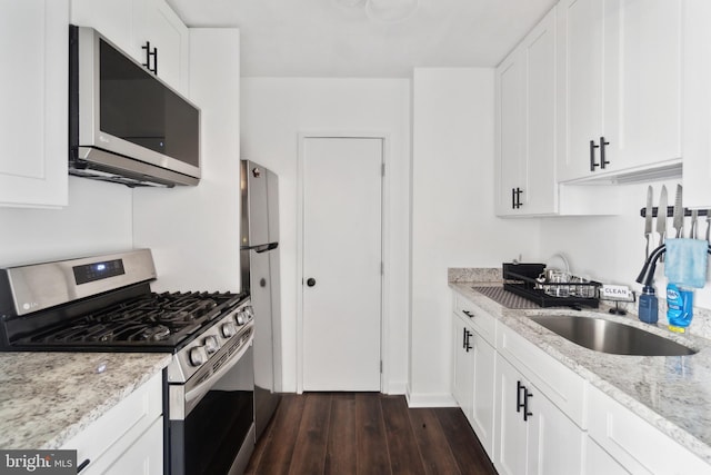 kitchen with light stone counters, stainless steel appliances, dark wood-type flooring, and white cabinetry