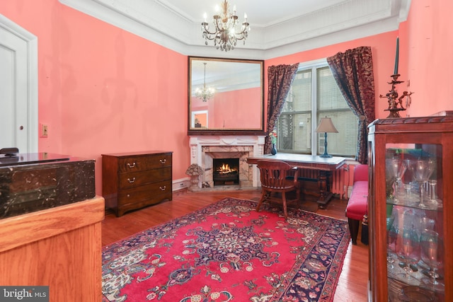 sitting room featuring wood-type flooring, crown molding, and an inviting chandelier