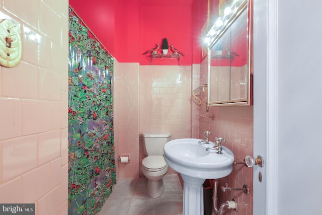 bathroom with tile walls, tile patterned flooring, toilet, and curtained shower