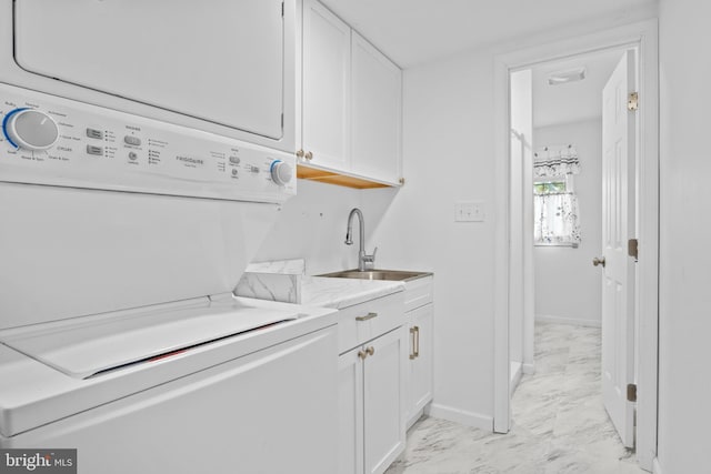 washroom with cabinets, stacked washer and dryer, and sink