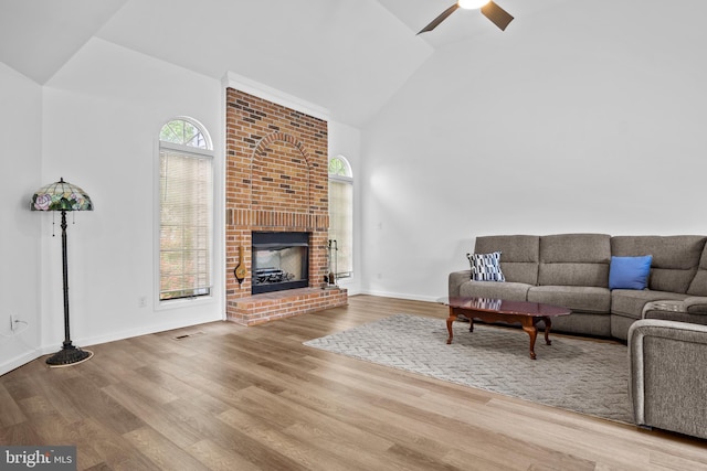 unfurnished living room with ceiling fan, hardwood / wood-style flooring, vaulted ceiling, and a brick fireplace