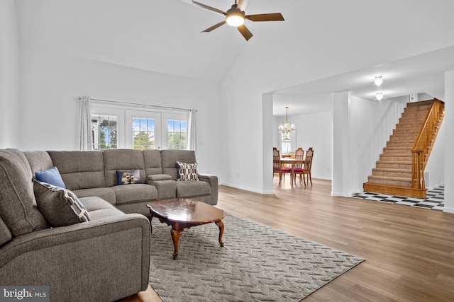 living room with high vaulted ceiling, french doors, ceiling fan with notable chandelier, and light wood-type flooring