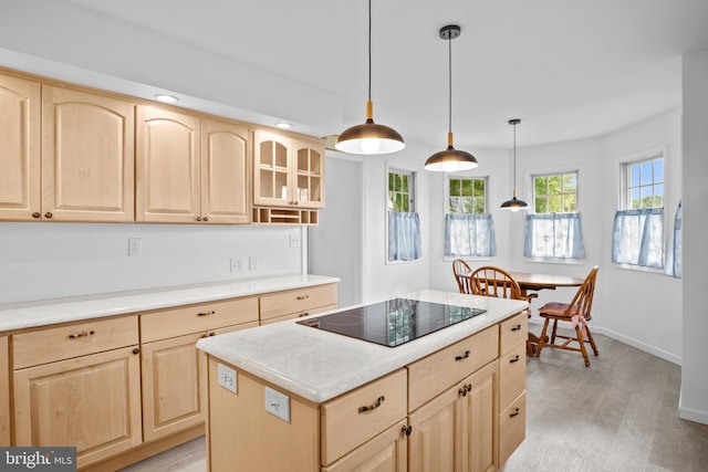 kitchen with black electric cooktop, hanging light fixtures, a center island, light brown cabinetry, and light hardwood / wood-style floors