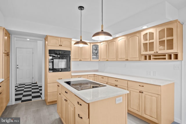 kitchen featuring light brown cabinets, light hardwood / wood-style flooring, hanging light fixtures, black appliances, and a center island