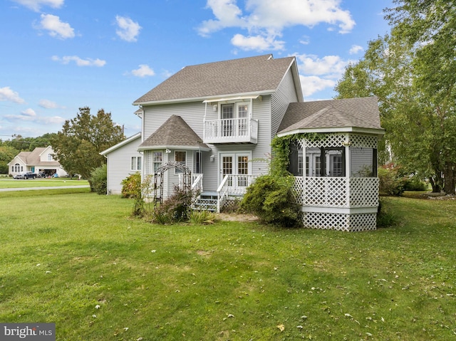 rear view of house with a yard and a balcony