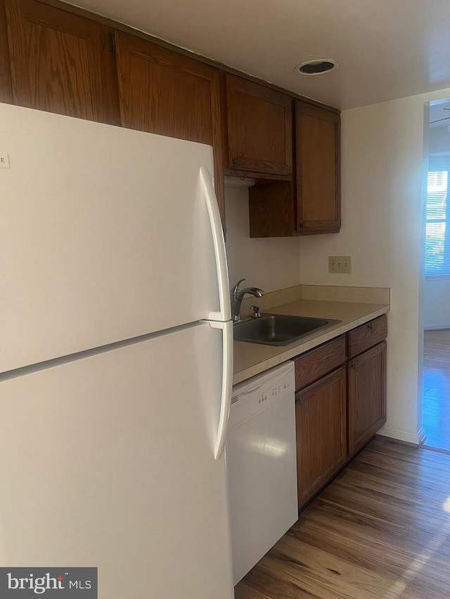 kitchen with light hardwood / wood-style floors, sink, and white appliances