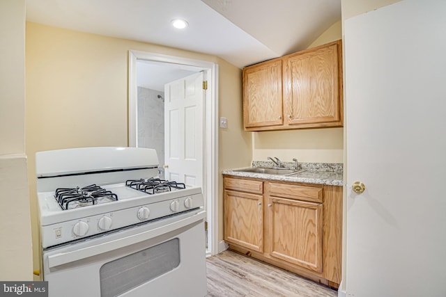 kitchen featuring white gas range, lofted ceiling, sink, light hardwood / wood-style floors, and light brown cabinetry