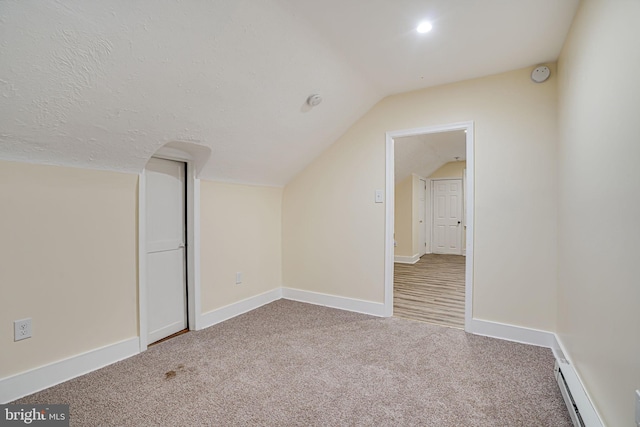 additional living space with baseboard heating, vaulted ceiling, and carpet