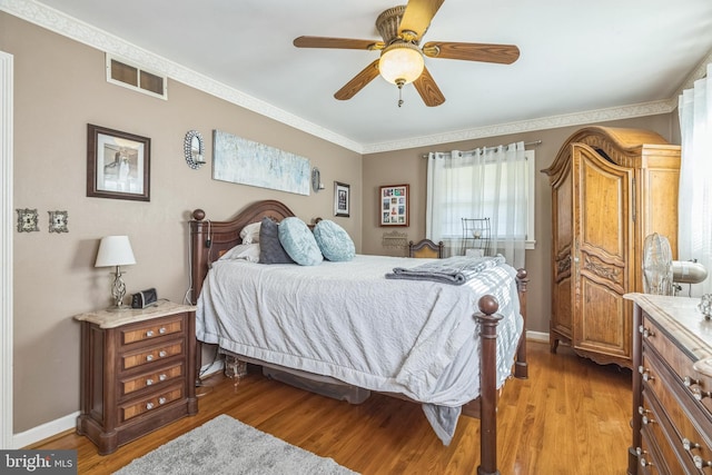 bedroom with wood-type flooring, crown molding, and ceiling fan