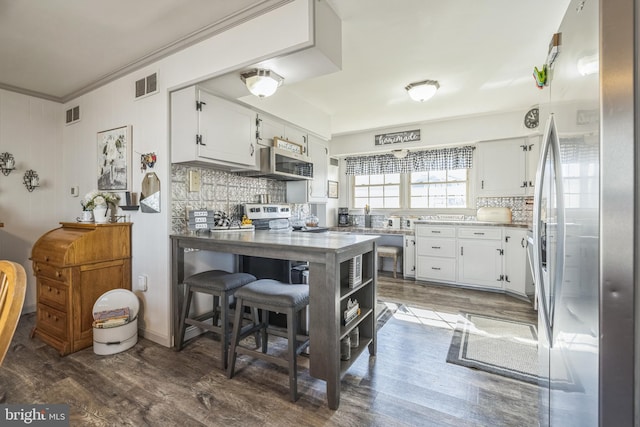 kitchen featuring white cabinets, appliances with stainless steel finishes, dark hardwood / wood-style flooring, and tasteful backsplash