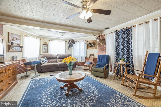 living area featuring crown molding, ceiling fan, light hardwood / wood-style floors, and brick wall