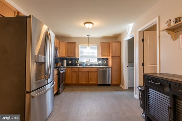 kitchen featuring hanging light fixtures, sink, backsplash, appliances with stainless steel finishes, and light wood-type flooring