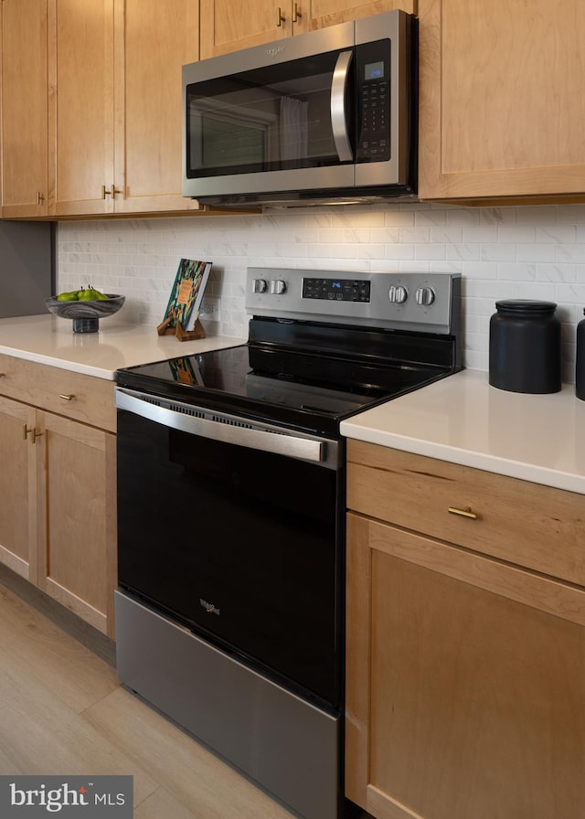 kitchen featuring stainless steel appliances, light brown cabinets, and backsplash