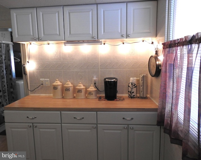 kitchen featuring white cabinets, decorative backsplash, and wood counters