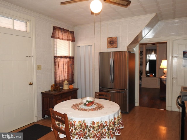 dining space with ceiling fan, hardwood / wood-style flooring, ornamental molding, and tile walls