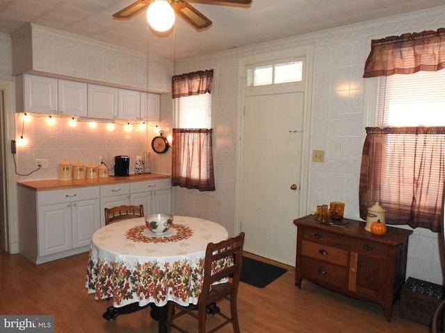 dining space featuring ceiling fan, tile walls, ornamental molding, and light hardwood / wood-style flooring