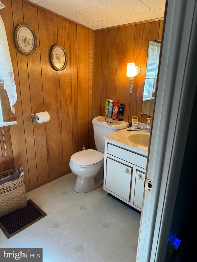 bathroom with vanity, wood walls, and toilet