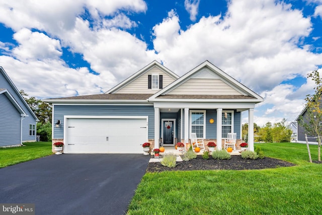 view of front of property featuring a front yard, a garage, and a porch