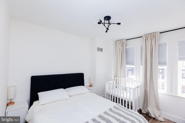 bedroom with wood-type flooring and a notable chandelier