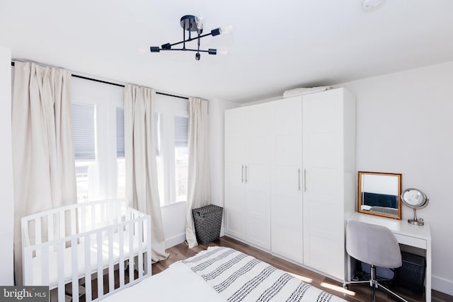 bedroom with a nursery area, hardwood / wood-style floors, and built in desk