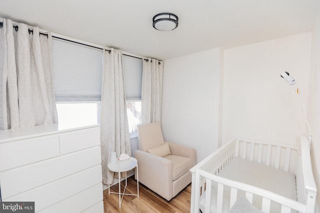 bedroom with light hardwood / wood-style floors and a nursery area