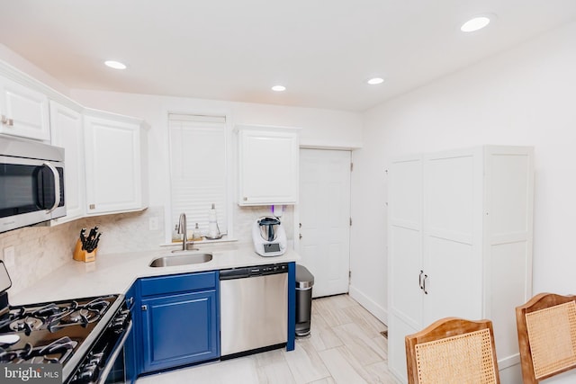 kitchen with sink, blue cabinetry, backsplash, white cabinetry, and appliances with stainless steel finishes