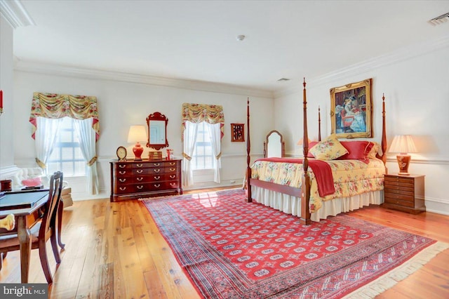 bedroom with light hardwood / wood-style floors, multiple windows, and ornamental molding