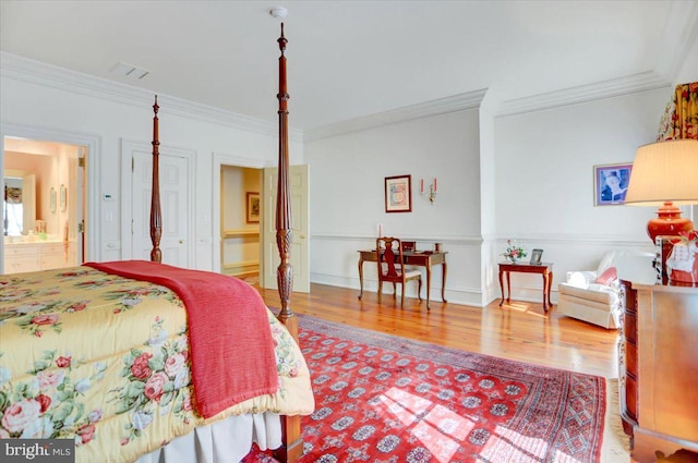 bedroom featuring ensuite bath, hardwood / wood-style flooring, and ornamental molding