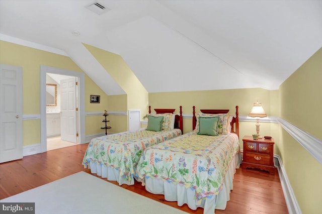 bedroom featuring lofted ceiling, wood-type flooring, and ensuite bathroom