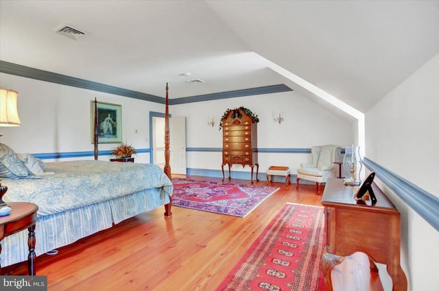 bedroom with ornamental molding, vaulted ceiling, and hardwood / wood-style flooring