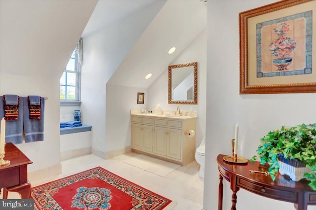 bathroom with tile patterned floors, vanity, vaulted ceiling, and toilet