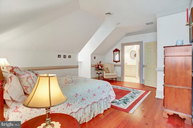 bedroom featuring ensuite bathroom, hardwood / wood-style floors, and vaulted ceiling