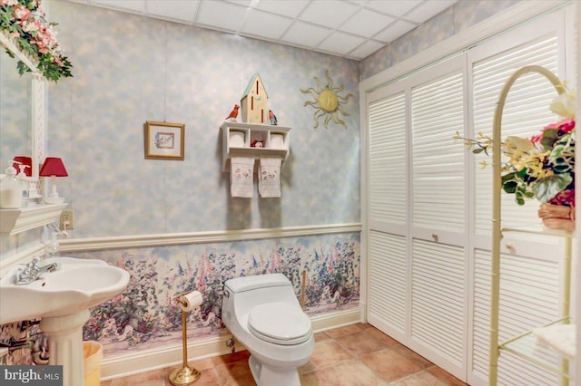 bathroom featuring tile patterned flooring, a paneled ceiling, toilet, and sink