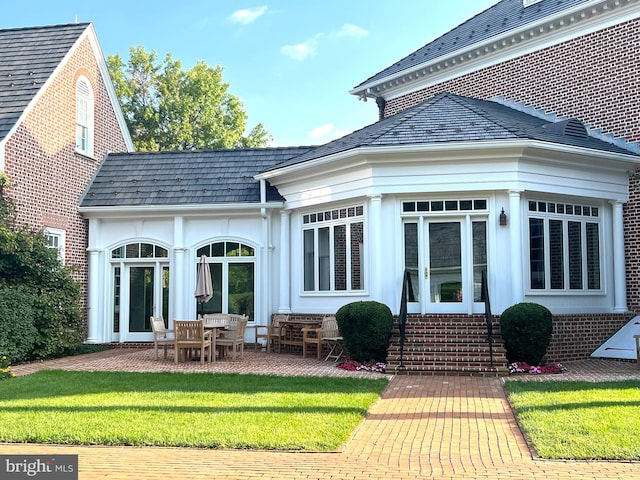 rear view of property featuring a patio area and a lawn