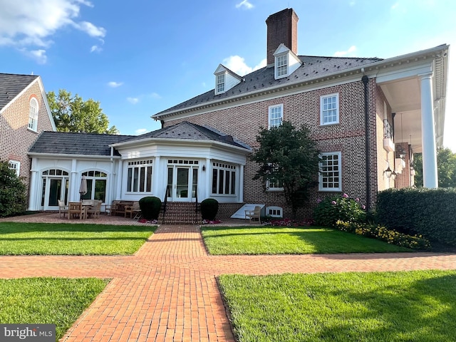 rear view of property featuring a lawn, a patio, and french doors