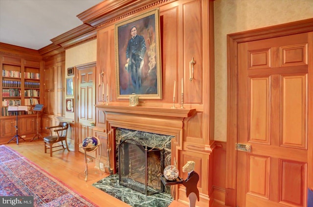 living area with light hardwood / wood-style floors, a premium fireplace, and crown molding