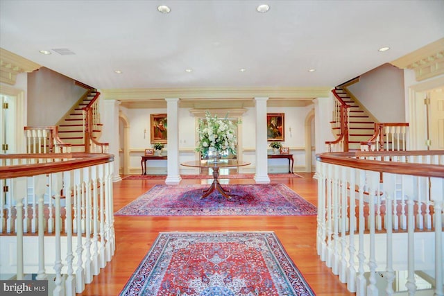 interior space featuring ornate columns, crown molding, and light hardwood / wood-style flooring