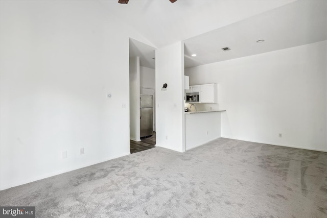 unfurnished living room featuring dark colored carpet, ceiling fan, and sink