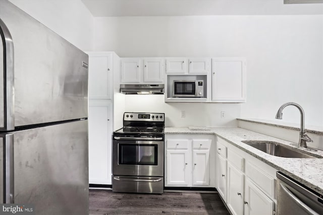 kitchen with white cabinets, light stone countertops, dark hardwood / wood-style flooring, stainless steel appliances, and sink