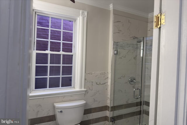 bathroom with toilet, crown molding, a shower with shower door, and tile walls