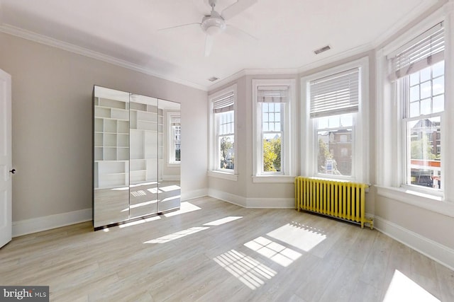 unfurnished sunroom featuring radiator heating unit, plenty of natural light, and ceiling fan