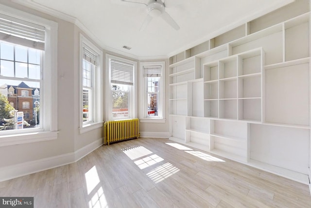 unfurnished sunroom featuring radiator and ceiling fan